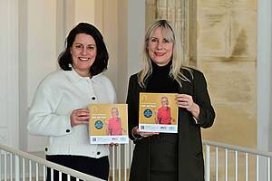 Regionalverbandsdirektorin Dr. Carolin Lehberger und vhs-Direktorin Nicole Boissier halten das neue vhs-Programm in den Händen und lächeln in die Kamera